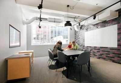 Modern meeting room with a dark table, grey chairs, and a feature wall.