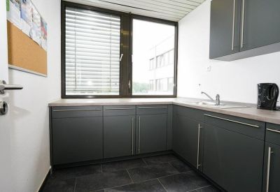 Compact modern kitchenette with dark grey cabinets and a large window.