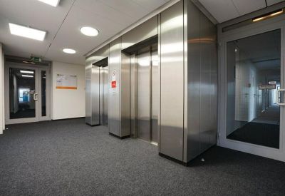 Elevator lobby with brushed metal doors and dark grey carpet.