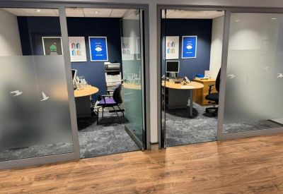 Two private glass-walled office suites with desks, chairs, and navy blue feature walls.
