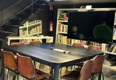 Professional meeting area with a dark wood table, leather chairs, and a wall-mounted screen.