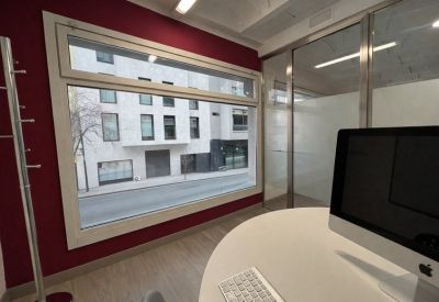 Office view through a large window overlooking the street with a red feature wall background.
