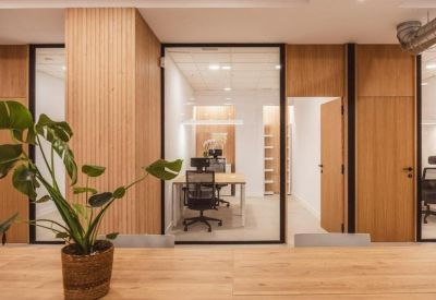 Private glass-walled office featuring light wood accents and ergonomic chairs.