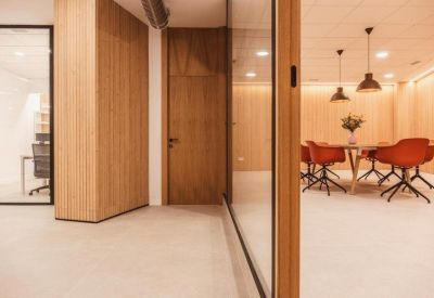 Meeting room with warm wood walls and vibrant orange swivel chairs.