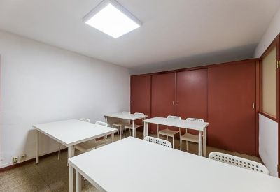 Communal workspace with multiple white tables and dark wood-style wall panels.