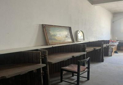 Row of rustic wooden workstations along a white wall featuring an ornate mirror and framed painting.