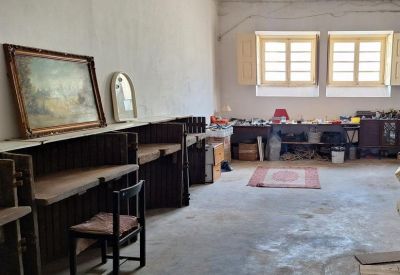 Spacious art studio area with wooden desks, paintings, and large windows with natural light.