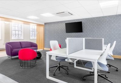 Collaborative office space with white desks and a vibrant purple sofa.