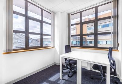 Private two-person office with white desks and large windows overlooking the city.