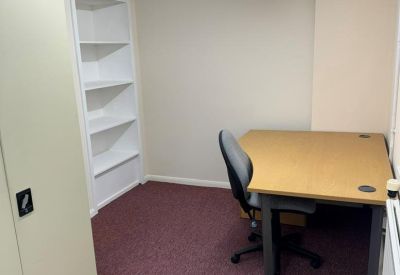 Private office featuring a wooden desk, ergonomic chair, and built-in shelving.