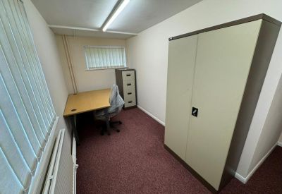 Small interior office with a desk, filing cabinet, and window blinds.