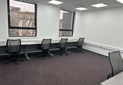 Bright office space featuring four workstations and ample natural light from two windows.