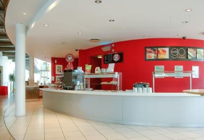 Bright reception desk area with a bold red feature wall and curved white counter.