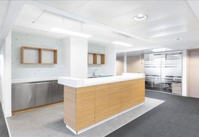 Communal break area with a wood-fronted island counter and modern kitchenette.