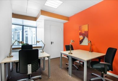 Bright office with a vibrant orange feature wall and two desks.