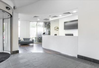 Modern reception area with a sleek white desk and glass revolving door entrance.