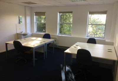 Private office suite featuring two large white desks and bright windows.
