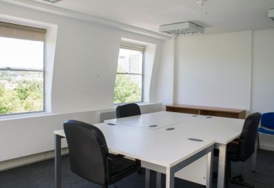 Spacious meeting room with white tables, black chairs, and large windows.
