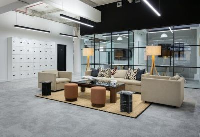 Reception lounge with a comfortable sofa, leather stools, and a stylish glass partition wall.