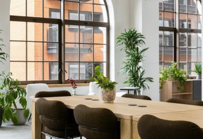 Close-up of a wooden meeting table with stylish dark brown upholstered chairs.