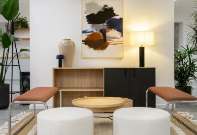 Modern lobby area featuring white cylindrical ottomans and bold abstract wall art.