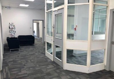 Reception area with glazed partitions and dark sofas.