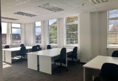Bright open-plan office space with white desks and black chairs.