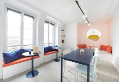 Vibrant communal breakout area with blue and orange banquette seating and café tables.