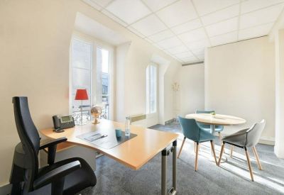 Bright private office featuring a wooden desk and a small round meeting table.