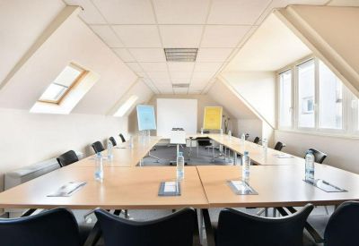 Large meeting room with a U-shaped table setup and natural light from skylights.