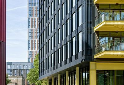 Street level view of the contemporary facade with black cladding and yellow balcony accents.