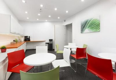 Vibrant communal breakout area with red and green chairs and a leaf-themed wall art.