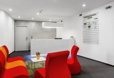 Modern reception area with a white desk and striking red and orange lounge seating.