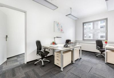 Bright private office suite with two desks and dark grey carpeting.