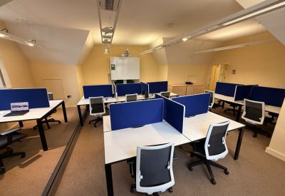 Open-plan office with white desks, blue partitions, and sloped ceilings