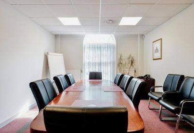 Professional boardroom with a long mahogany table and black leather chairs.