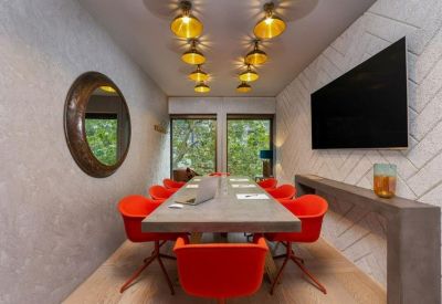 Long meeting table with bright red chairs and a patterned feature wall.