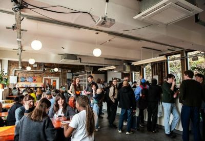 Bustling cafe and dining area with high ceilings and people gathered around tables.