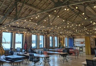 Spacious open-plan workspace with a high timber-beamed ceiling and string lights.