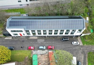 Aerial view of the building featuring a large rooftop solar panel installation.