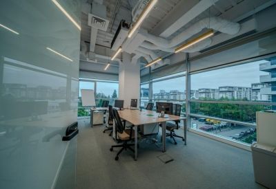 Bright corner office with multiple desks and floor-to-ceiling windows.