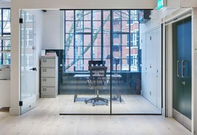 Private office pod with glass walls and views through industrial windows.