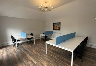 Bright office suite with wood flooring, three white desks, and a decorative chandelier.