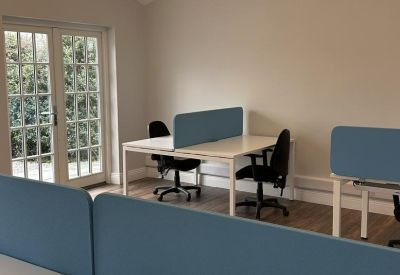 Office workspace featuring white desks with blue privacy dividers and a gold light fixture.