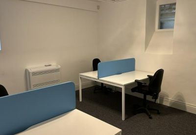 Bright private office suite featuring white desks with blue privacy screens and black rolling chairs.