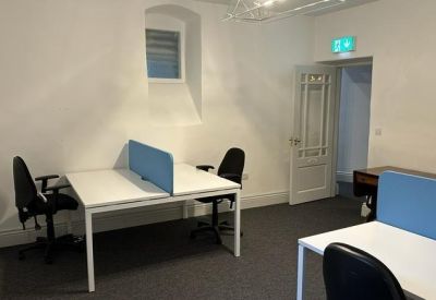 Office room with multiple desks, blue partitions, and a traditional window niche.