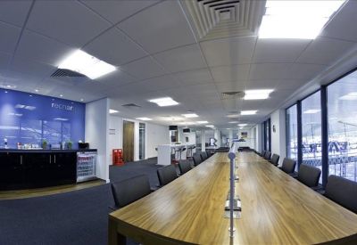 Coworking space with long communal wooden tables and window views.