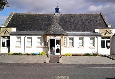 Wide exterior facade of the white building with a dark slate roof and symmetrical window layout.