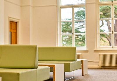 Modern breakout area with lime green seating and large windows overlooking trees.