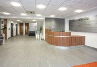 Modern reception area featuring a curved wooden desk and bright recessed lighting.